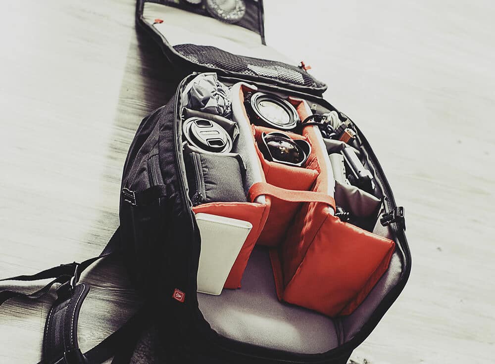 An open camera backpack with lenses and a DSLR camera inside