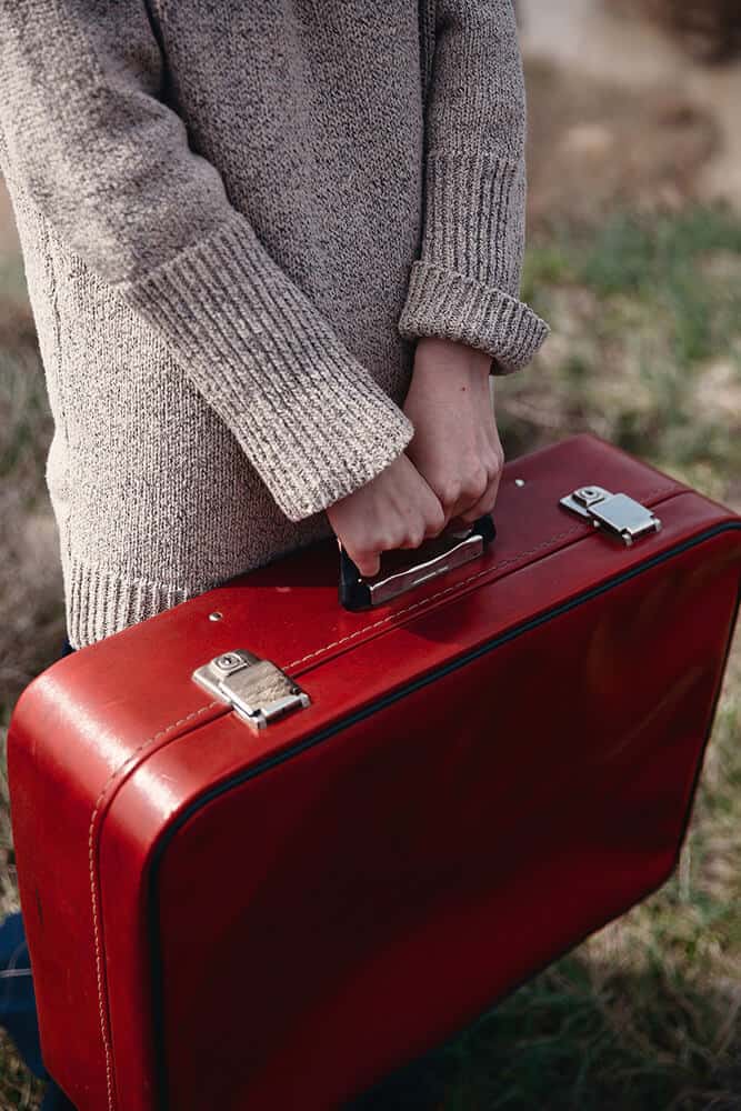 Donna che trasporta una valigia rossa 