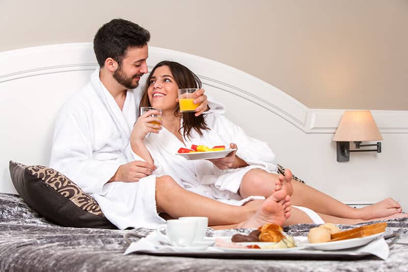Couple having breakfast in bed during their honeymoon