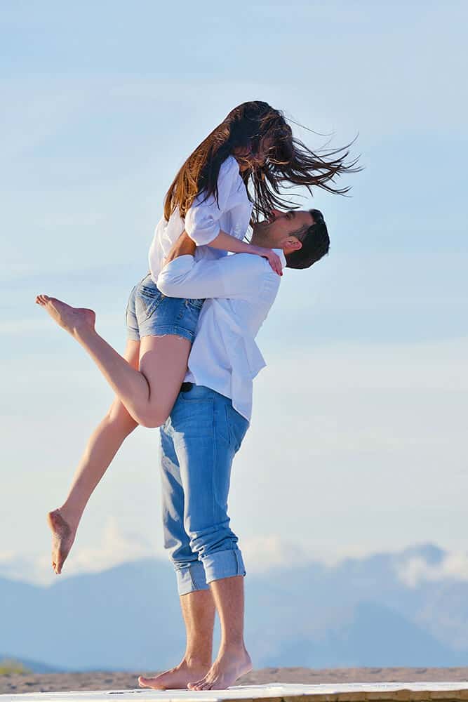 Young Couple hugging and jumping on the beach