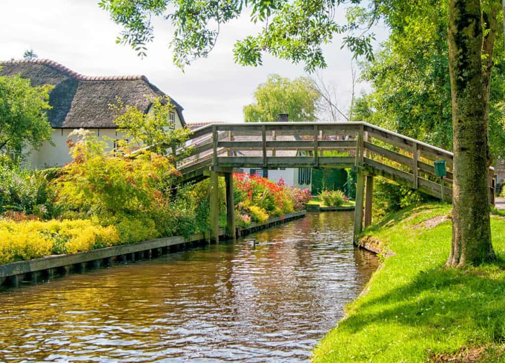 Wooden bridge on a narrow canal in Giethoorn, the perfect day trip from Amsterdam