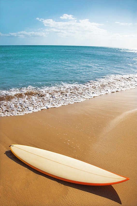 White surfboard laying on the sand at one of the beaches on the road to Hana in Maui