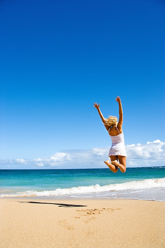 Ragazza salta di gioia su una spiaggia alle Hawaii