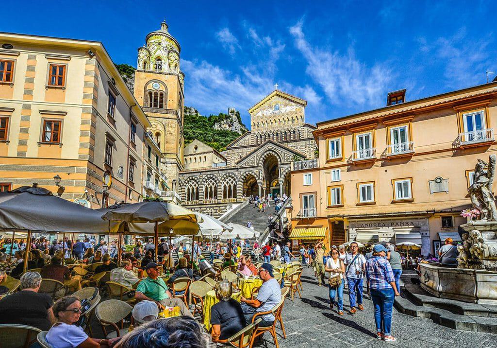 Amalfi mains quare with its Duomo and tables with people sitting to eat gelato