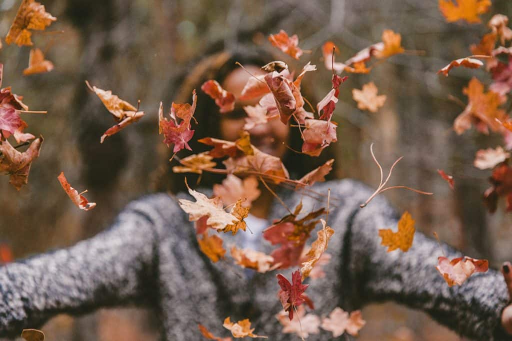 Girl throwing Fall leaves in the air