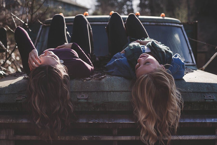 Girl friends talking on the hood of an old Ford truck