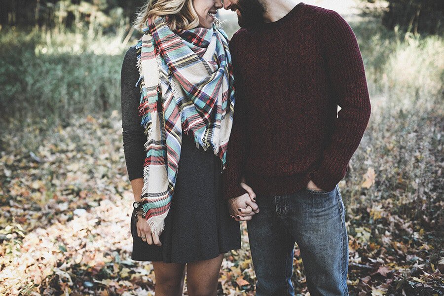 Young couple in love holding hands in the forest in fall