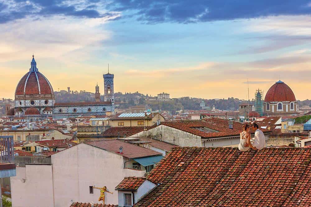 Coppia di innamorati osserva il tramonto sulla città di Firenze dal tetto di una casa