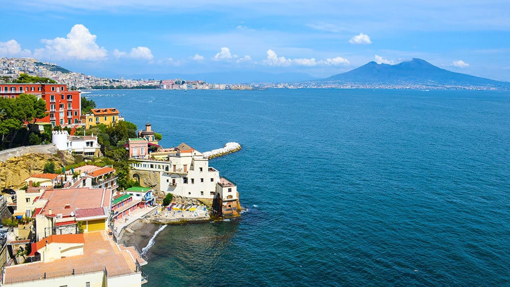 Gulf of Naples seen from above, with colorful houses and historical building along the coast