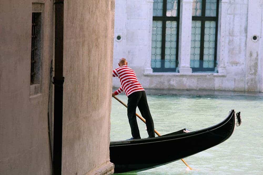 Gondolier on a gondola in a romantic canal in Venice (Italy)