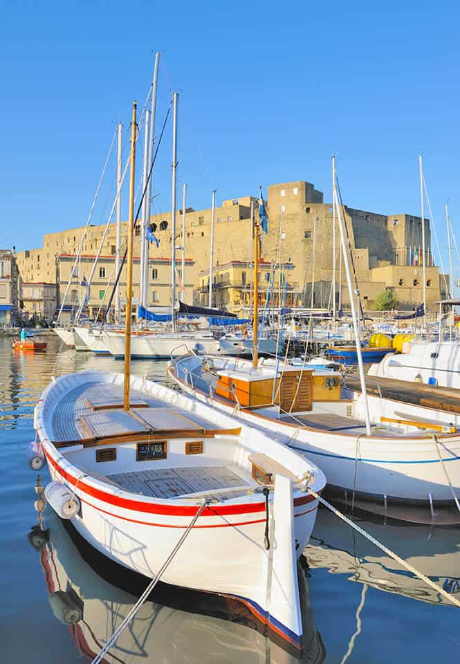 Fishermens boats at Borgo Santa Lucia with a romantic view of Castel dell'Ovo in Naples (Italy)