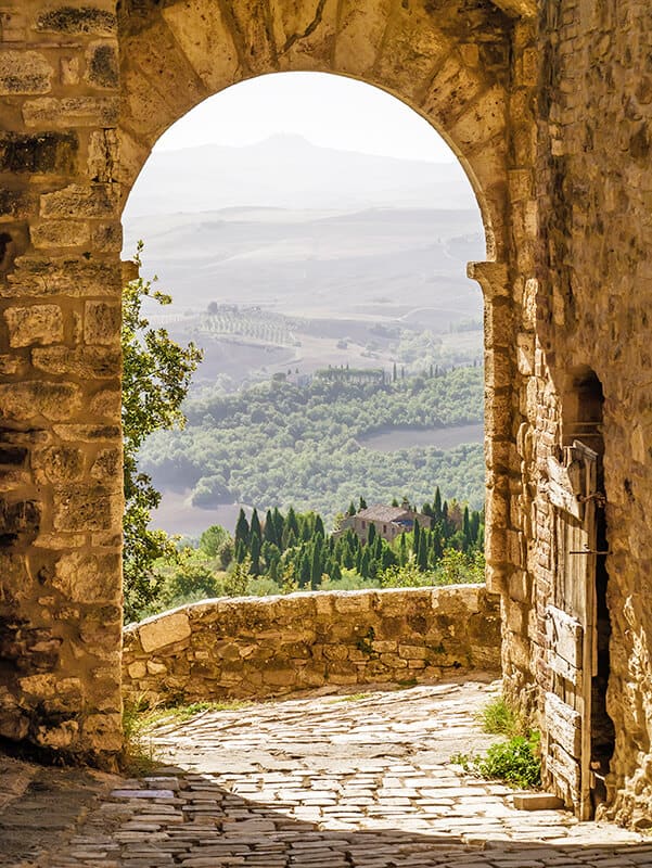 Stone arch with a romantic view on a green valley in Tuscany, Italy