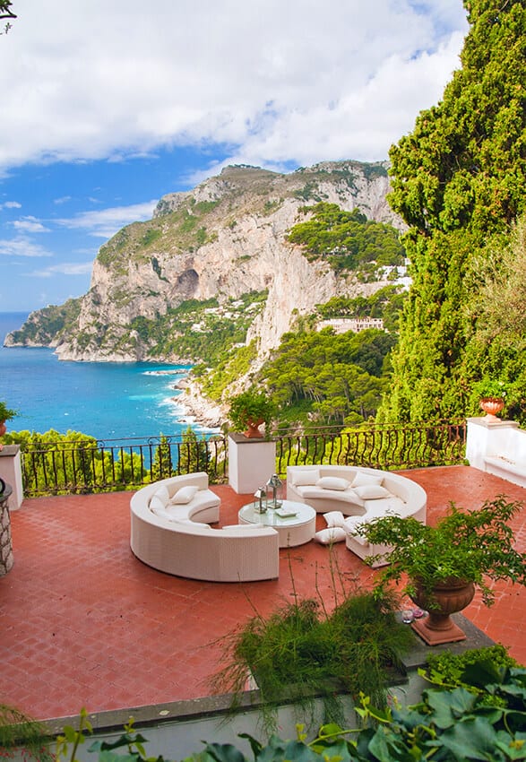 Terrazza romantica con divani bianchi e panorama sul Golfo di Napoli sull'isola di Capri