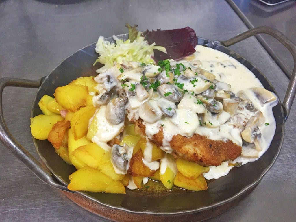 Kotlet schabowy served with mushrooms and potatoes
