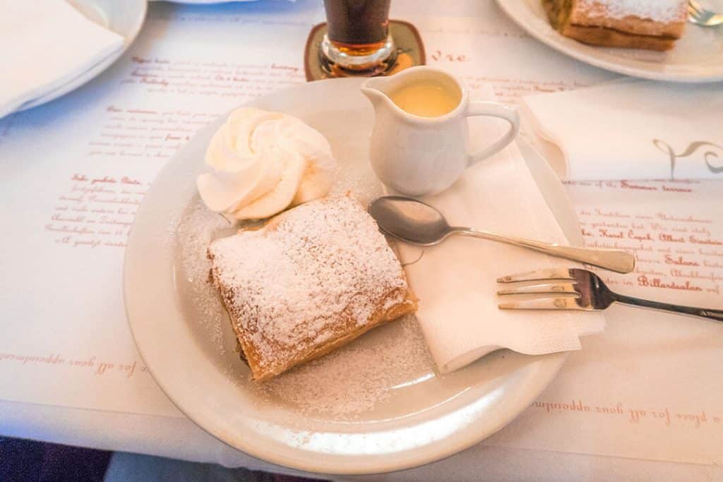 Strudel di mele con zucchero a velo, panna montata e un bricco di caramello, al Cafe Louvre di Praga