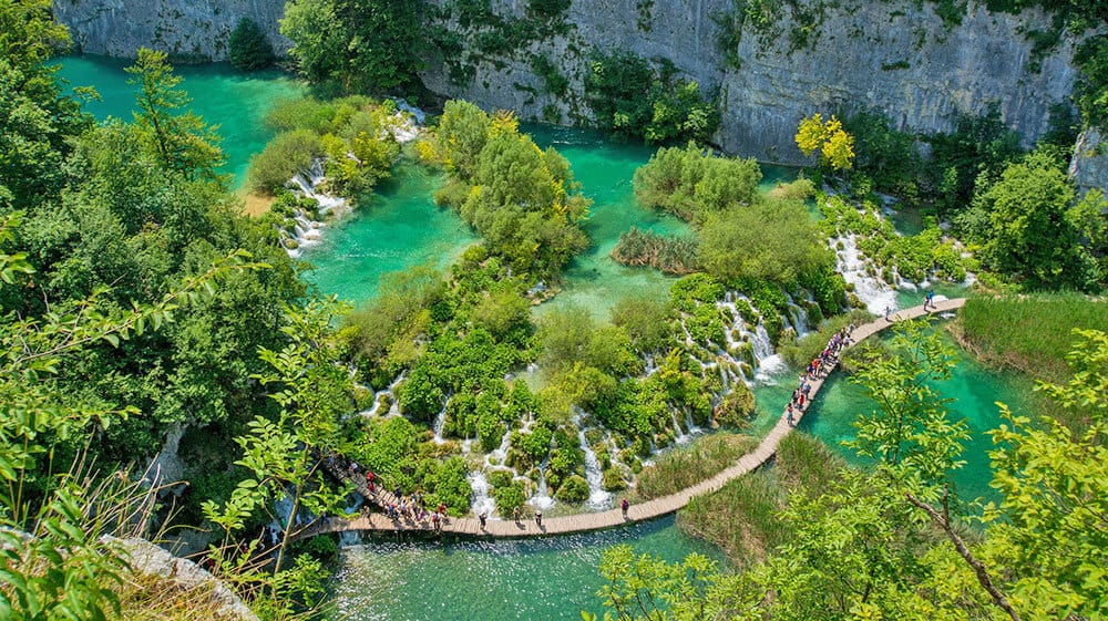 A trail in the lakes area with tourists walking above the water