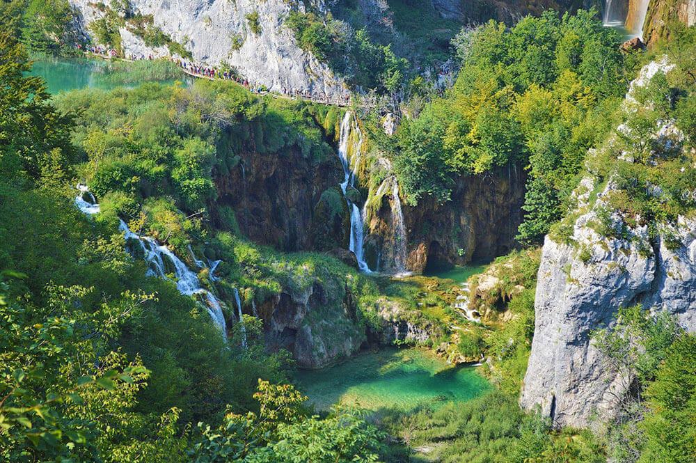 Panoramica dall'alto di un sentiero che costeggia la montagna appena sopra due piccole cascate