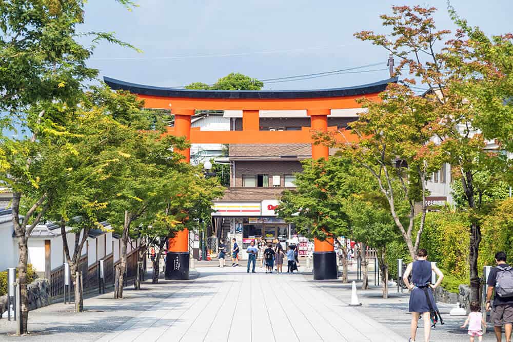 Fushimi Inari Shrine - La grande porta Romon vista dall'edificio principale del santuario. Sullo sfondo la stazione Inari