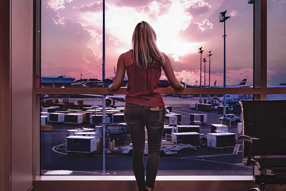 Planning a trip to Hawaii on a budget - Girl looking out of the window at Honolulu airport