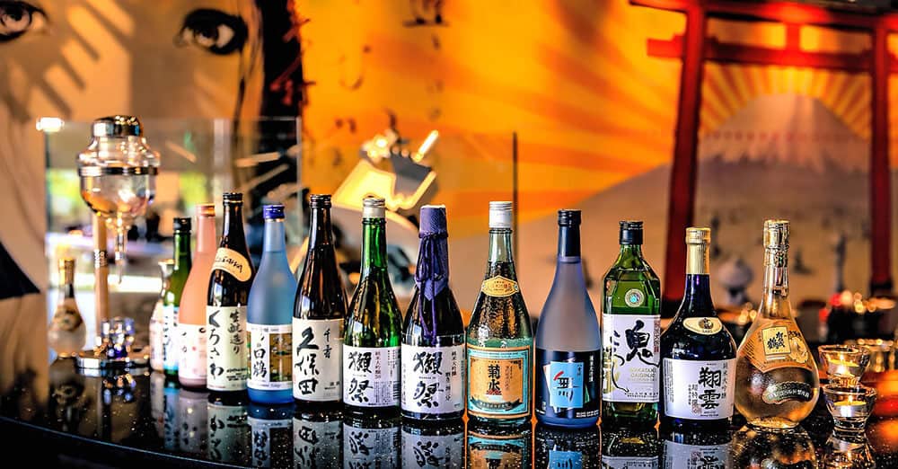 Cosa comprare in Giappone - Bottiglie di sake di forme diverse allineate sul bancone di un bar
