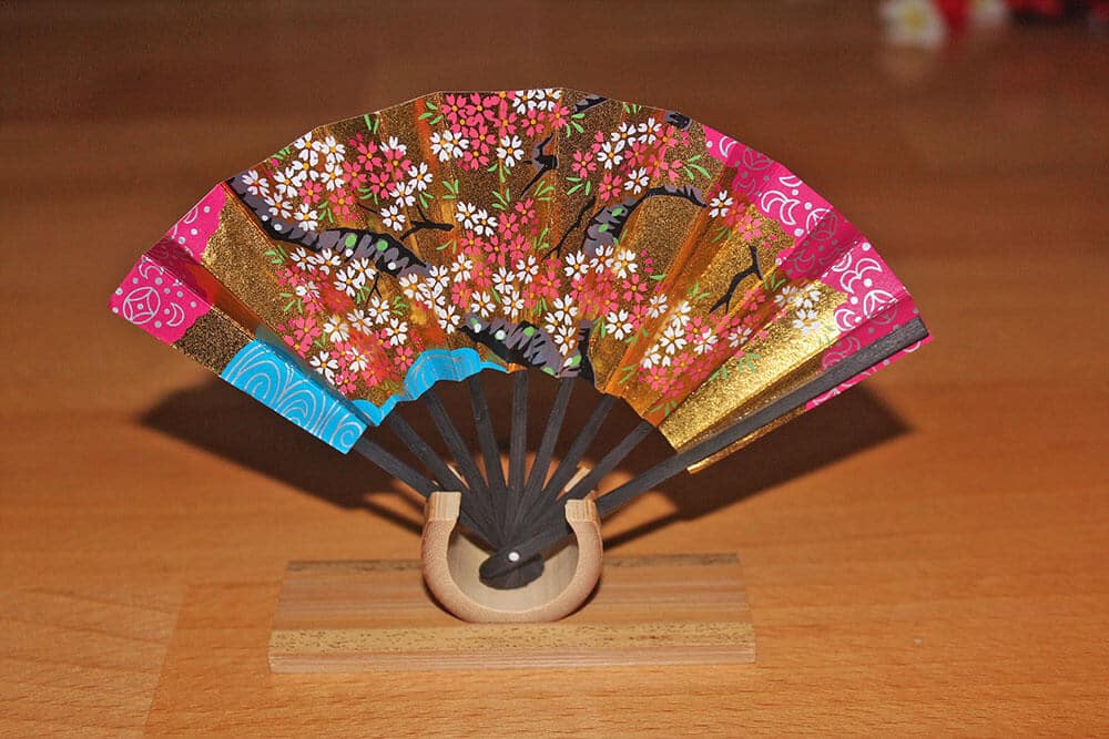 Best souvenirs from Japan - A lovely Japanese folding fan in pink, golden and blue, decorated with cherry blossoms