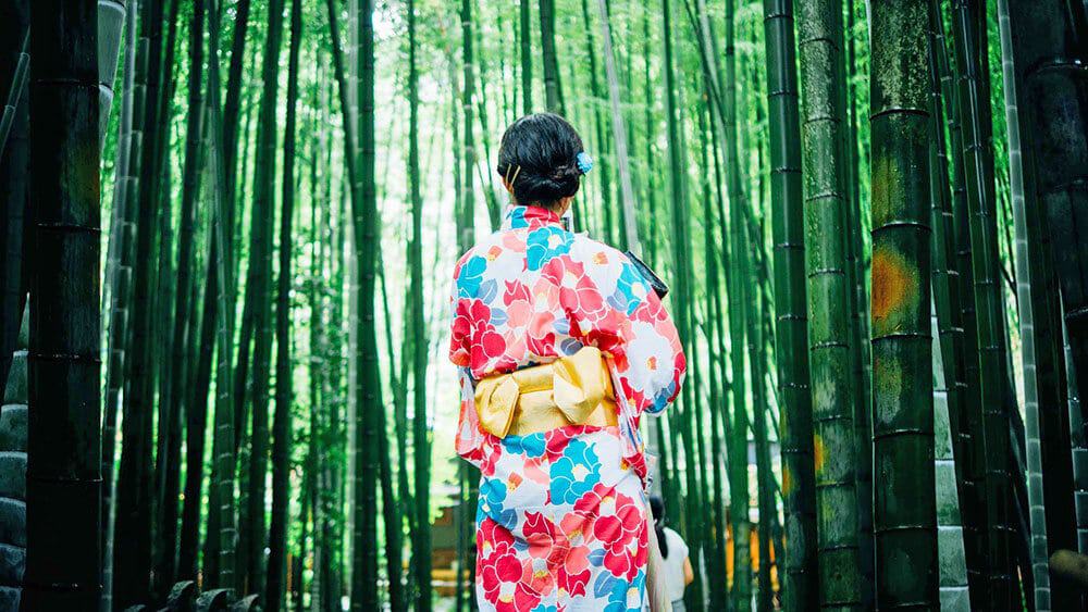 Cosa comprare in Giappone - Una ragazza con indosso un colorato kimono, sullo sfondo la foresta di bambù di Arashiyama