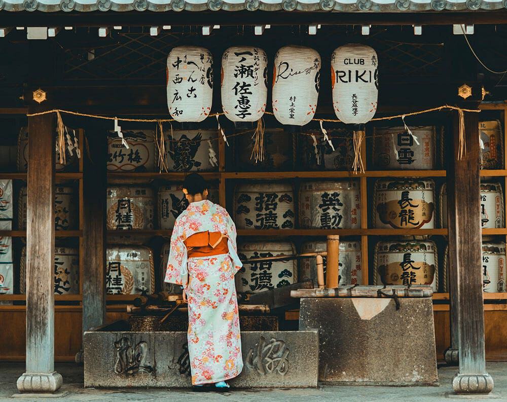 Cosa comprare in Giappone - donna con indosso un kimono si purifica le mani a un santuario giapponese