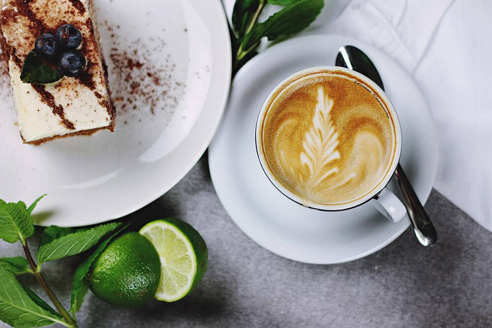 Una tazza di cappuccino accompagnata da una fetta di dolce semifreddo