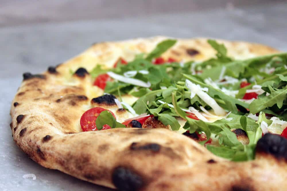 Pizza from Naples (Italy) with soft crust, arugula, mozzarella cheese and tomatoes