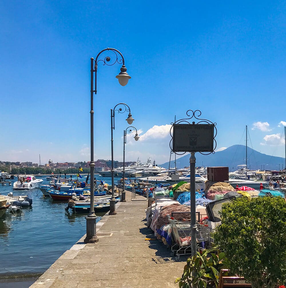 Posti da visitare a Napoli | Una foto del vialetto coi lampioni, tra reti da pesca e barchette, a Mergellina