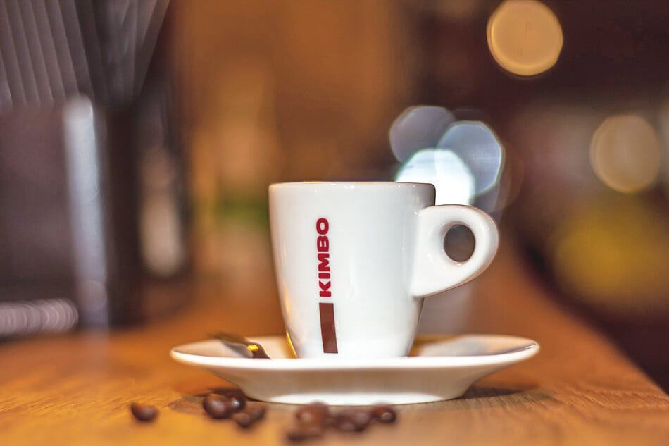 Caffè napoletano - Una tazza di caffè Kimbo e qualche chicco di caffè sul bancone del bar