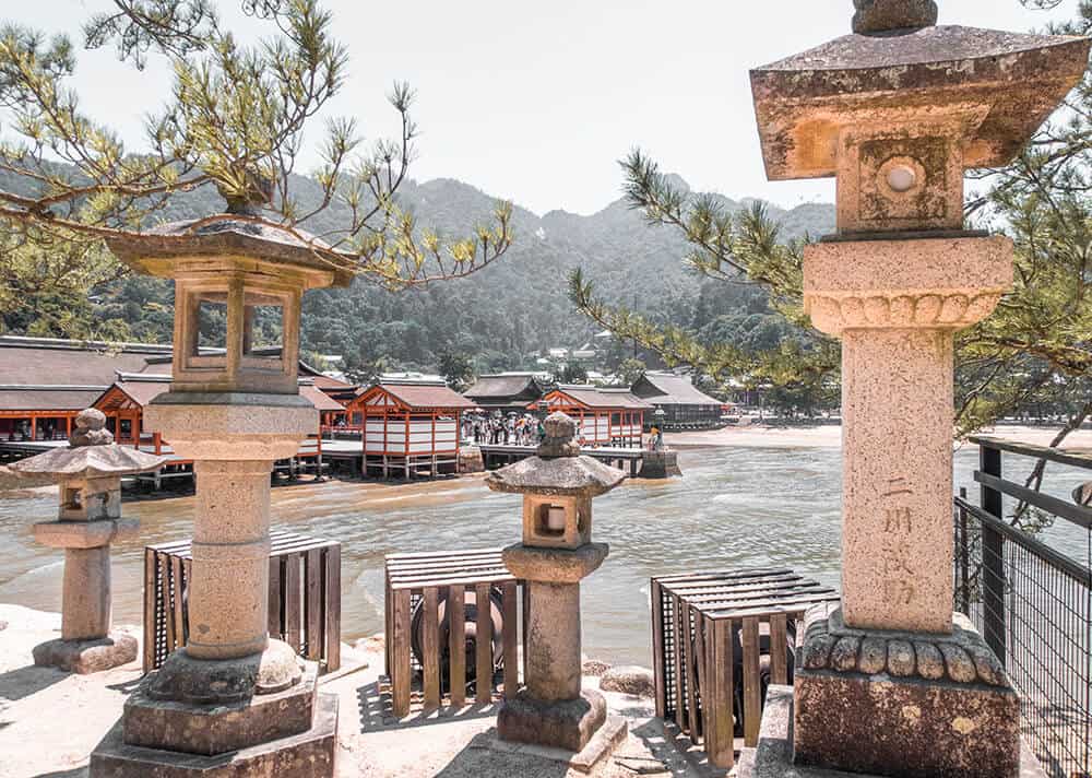  Viaggio in Giappone | Lanterne in pietra con il mare e il santuario di Itsukushima sullo sfondo, a Miyajima