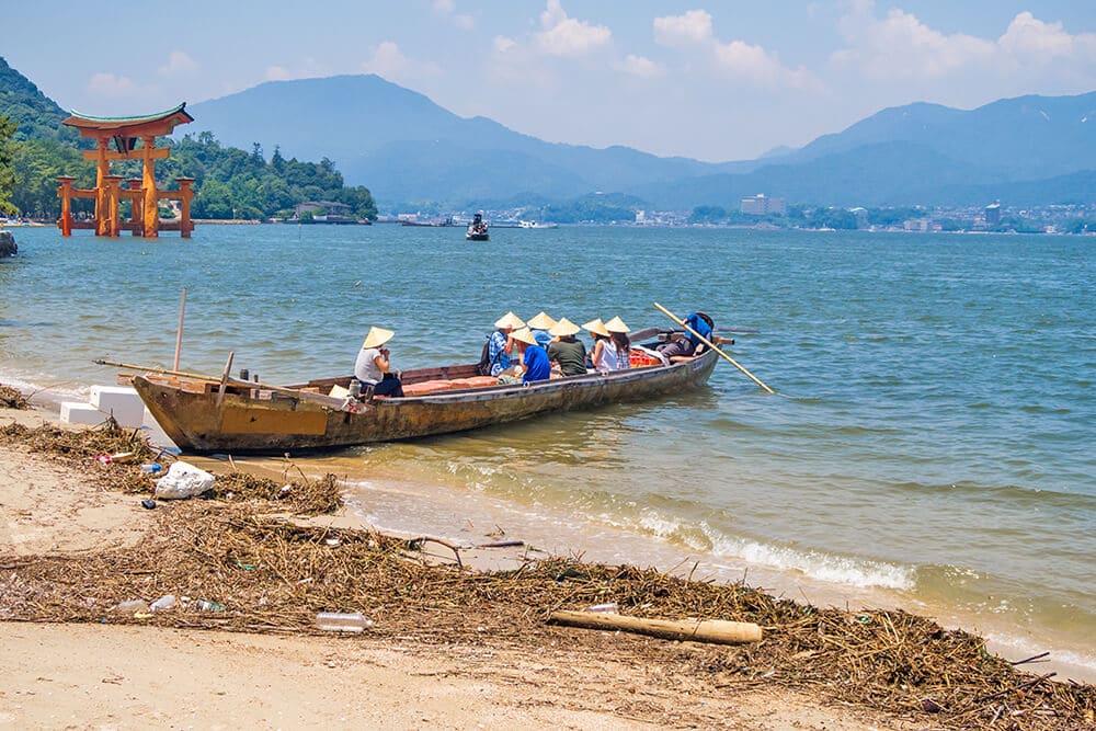 Things to do in Miyajima | Long wooden canoe full of tourists off the coast of Miyajima