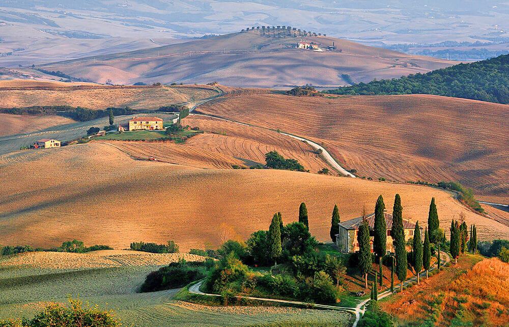 Traditional Tuscany countryside: hills, a brick house and a lonely road