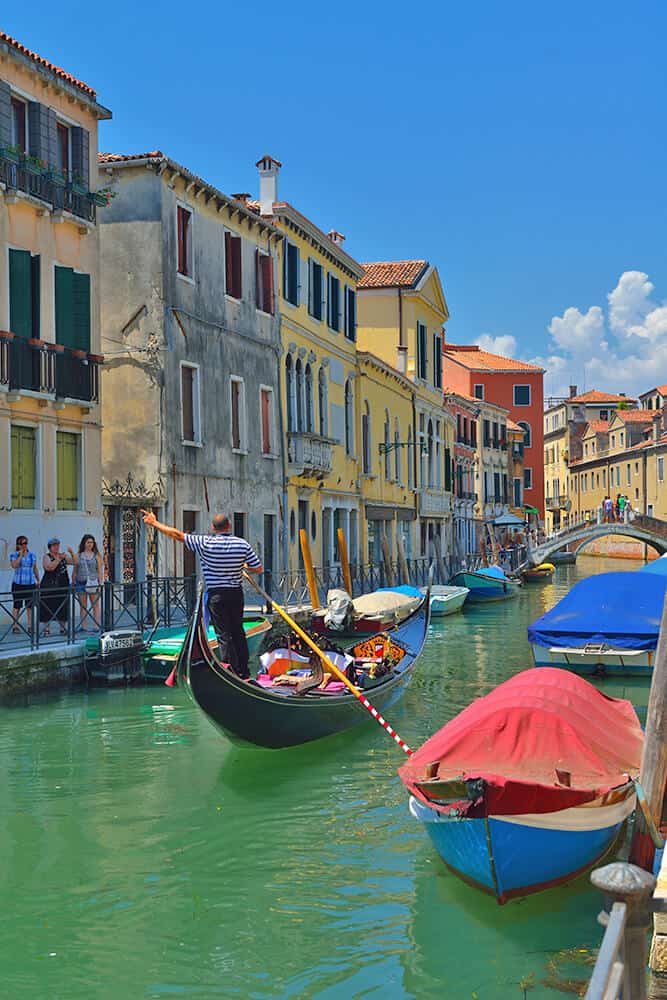 Gondola in Venice (Italy) with gondolier talking to people on the shore