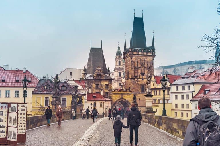 Prague in Winter - Crossing Charles Bridge in Prague with snow on the street