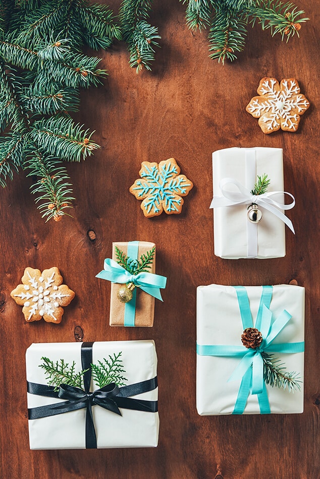 Regali di Natale impacchettati con nastri colorati accanto a biscotti al burro delle feste