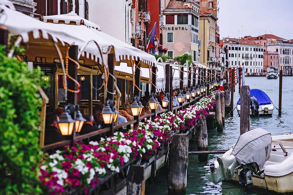 Vasi di fiori colorati accanto a un ristorante che affaccia su uno dei canali di Venezia in inverno