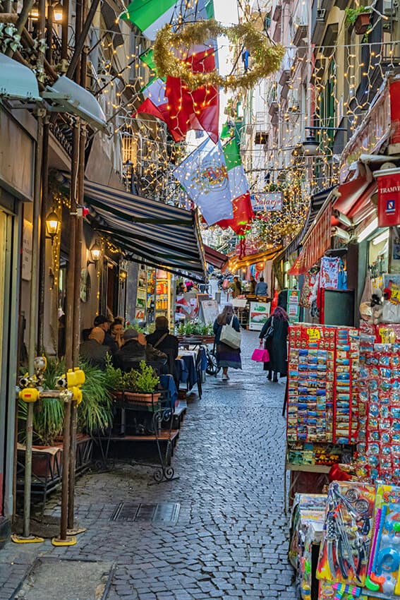 Naples (Italy) narrow street with Christmas lights and souvenir vendors