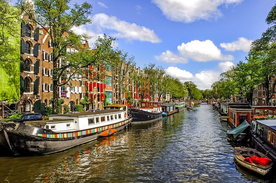 Uno dei tanti canali da visitare ad Amsterdam in una giornata soleggiata con imbarcazioni lungo le sponde