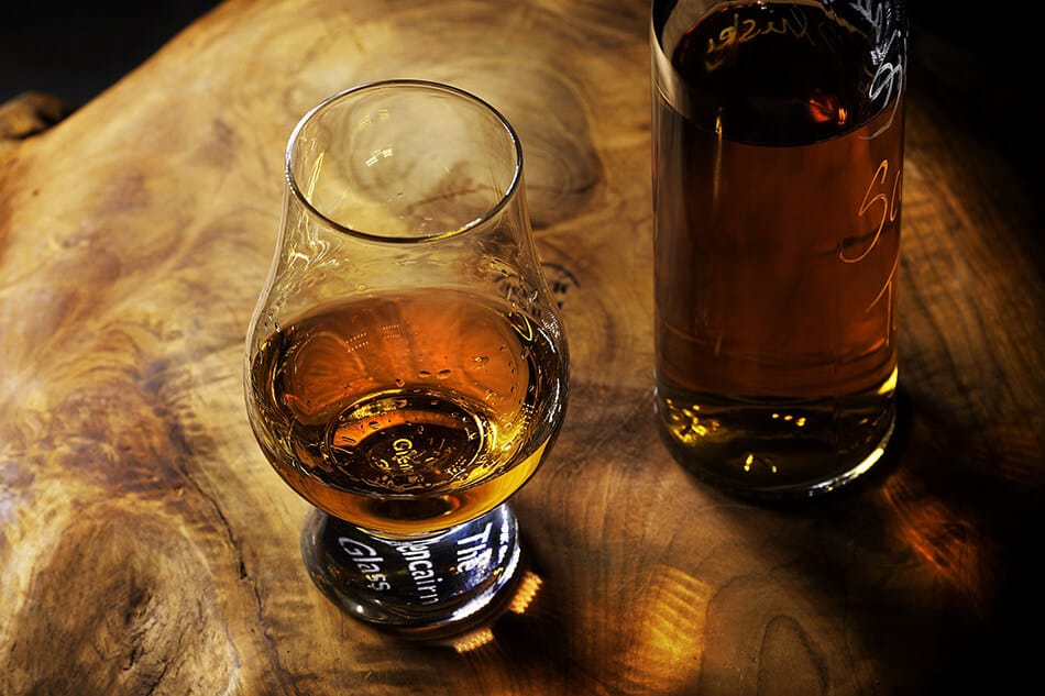 Una bottiglia di whisky irlandese accanto a un bicchiere mezzo pieno