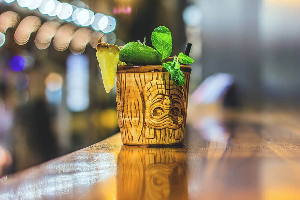 Cocktail with a slice of pineapple and fresh mint served in a tiki mug in a bar at Waikiki Beach