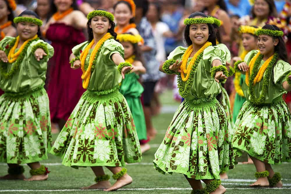 Children dressed in traditional costumes dancing hula at a luau in Waikiki