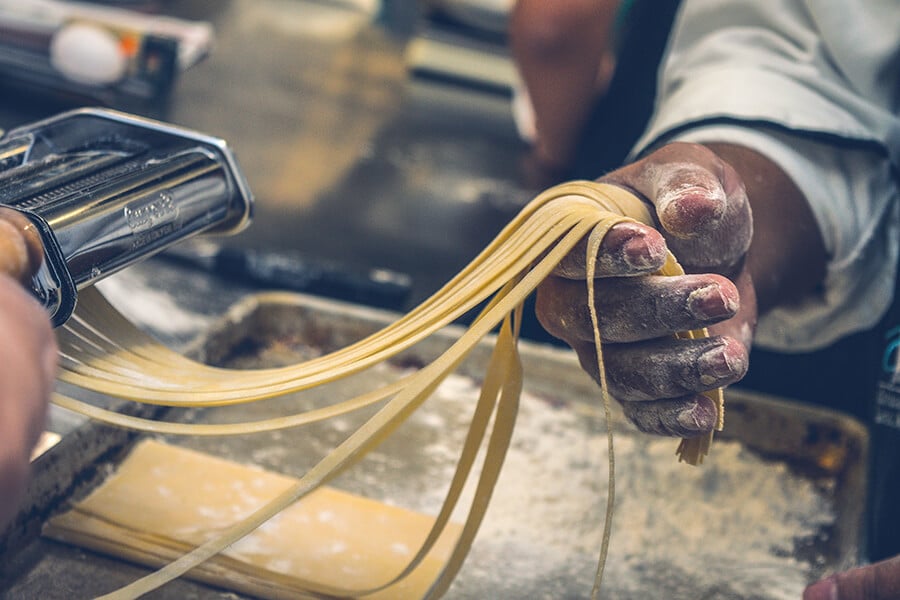 Italian chef making fresh tagliatelle pasta on a cooking lesson