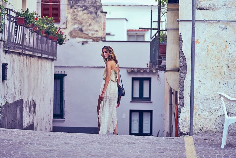 Woman wearing a flowy white dress while walking in one of the villages of the Amalfi Coast