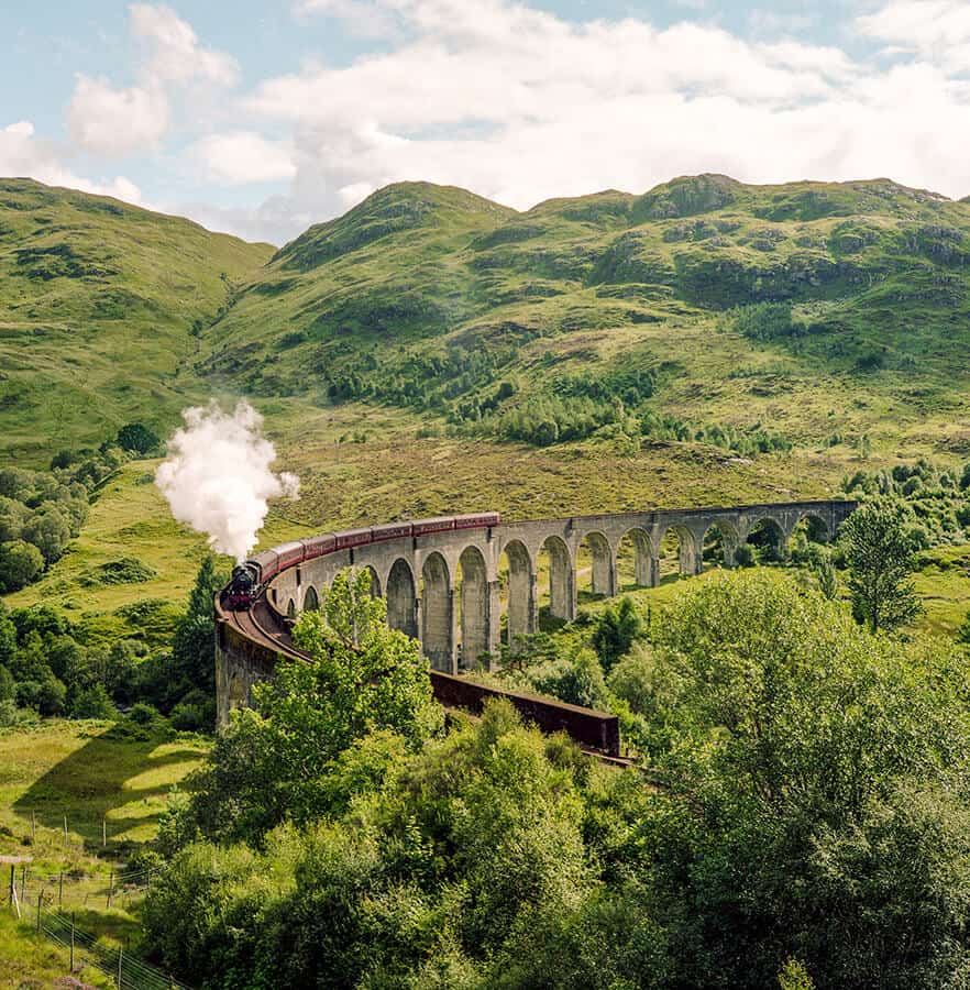 Panoramica dell'iconico ponte in pietra con il treno a vapore Jacobite steam train