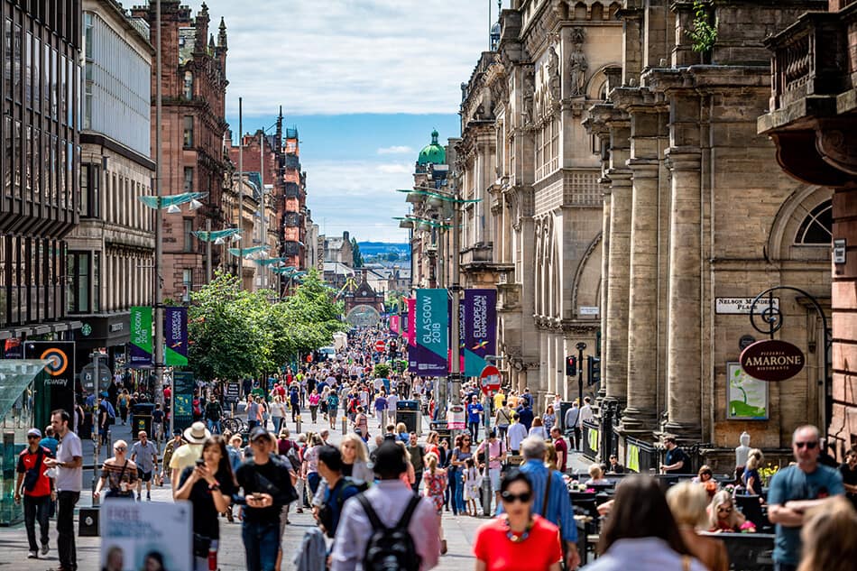 Busy street in Glasgow lined with historic buildings and shops