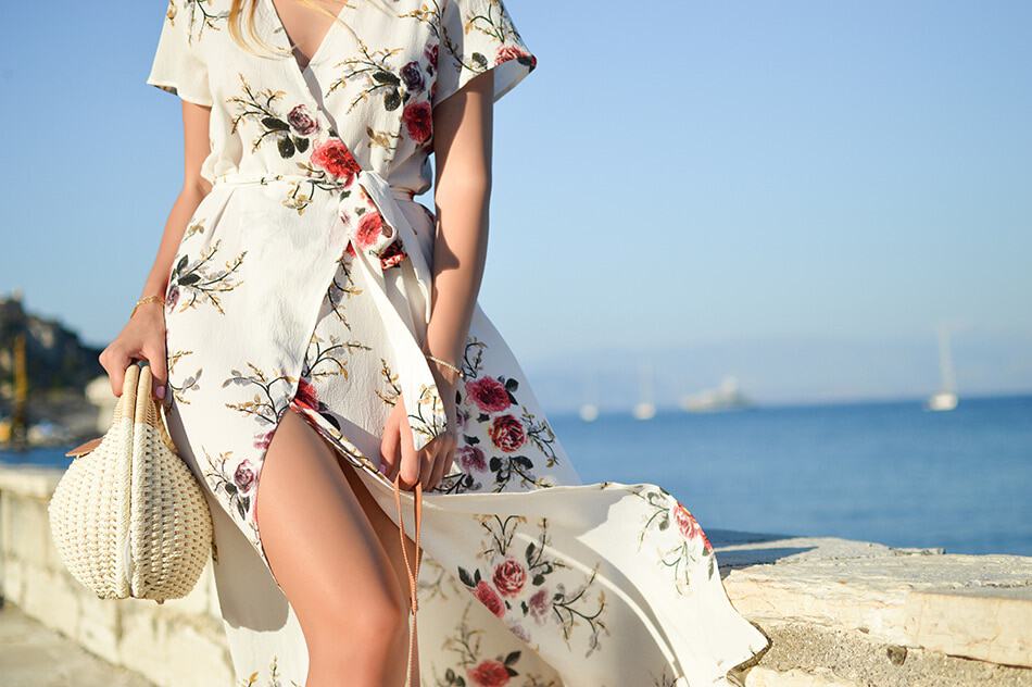 Close up on a woman wearing a flowy wrap dress with a flower print on an Italian beach 