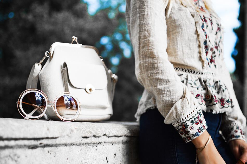 Un paio di occhiali da sole alla moda, una borsa bianca e una ragazza con indosso una tunica ricamata