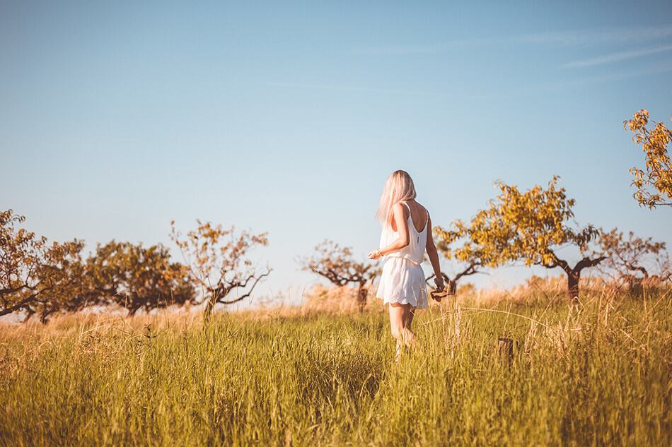 Girl wearing a Positano dress walks in a barley field in Puglia, Italy
